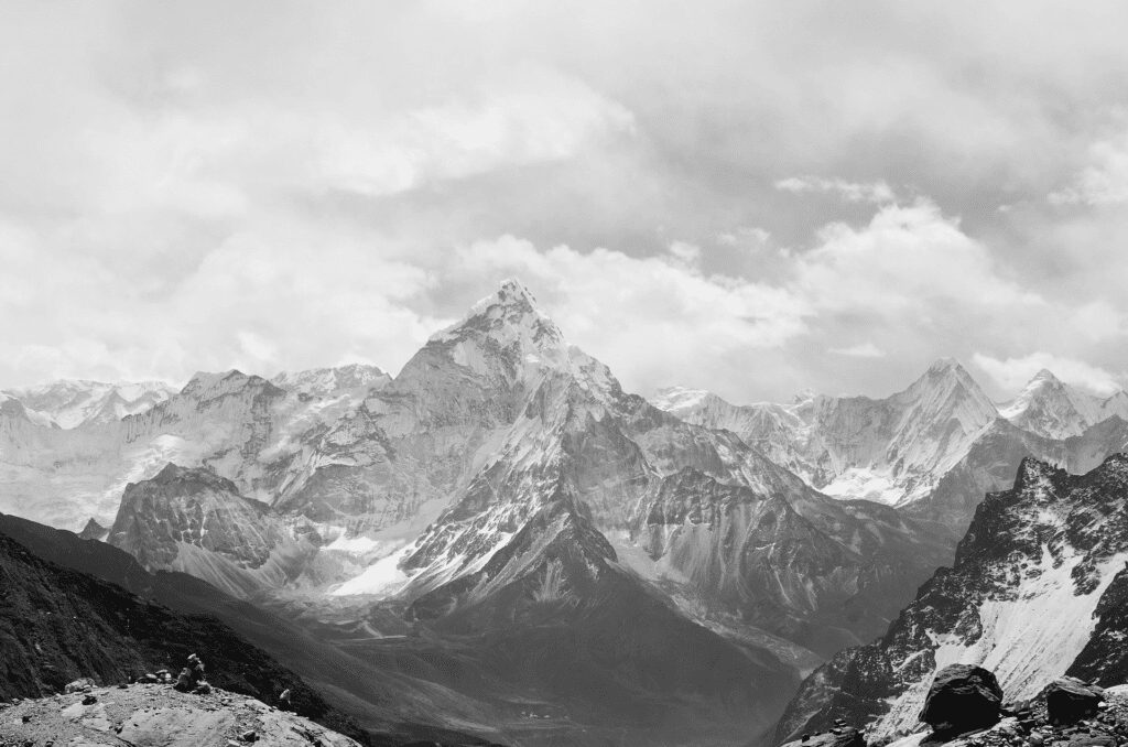A black and white photo of mountains with clouds in the sky.