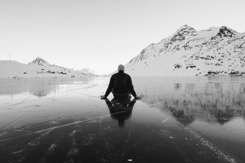 A man sitting on the ice of a lake.