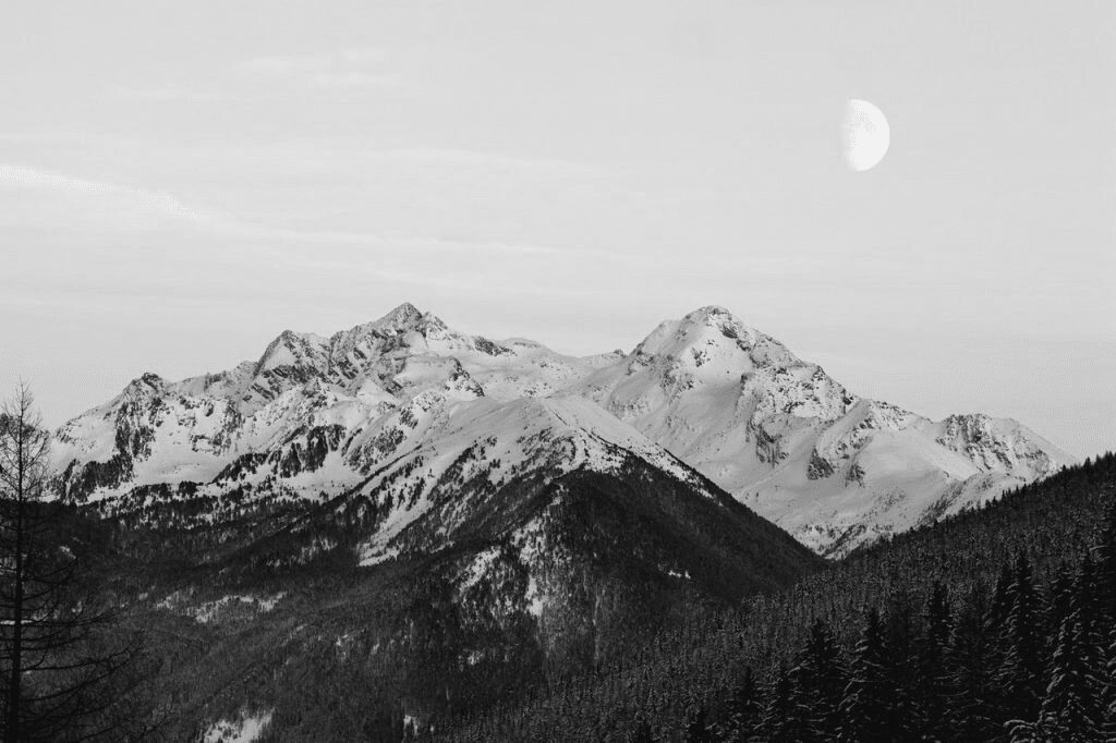 A black and white photo of mountains with snow on them.