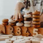 Child's hand interacting with wooden educational toys and number blocks indoors.