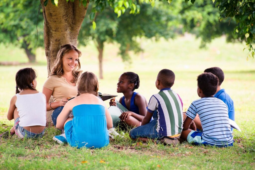 Group of kids sitting under a tree.