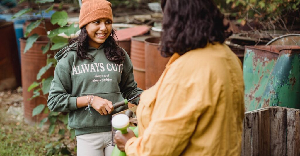 Cheerful ethnic teenager speaking with anonymous gardener with watering can while looking away on farm in daylight
