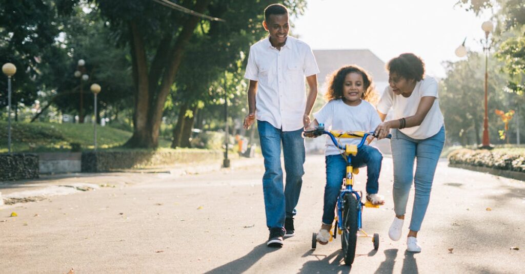 Happy family teaching their child to cycle on a sunny day outdoors.