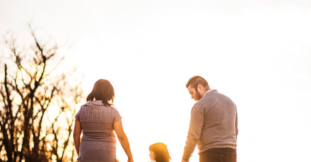 A family of three walks hand in hand at sunset, enjoying togetherness and warmth.