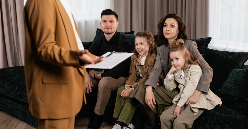 A family sits on a couch while talking to a real estate agent about buying a house.