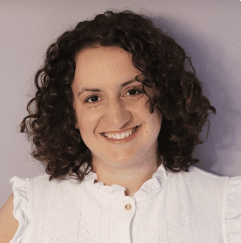 Smiling woman with curly hair wearing white blouse