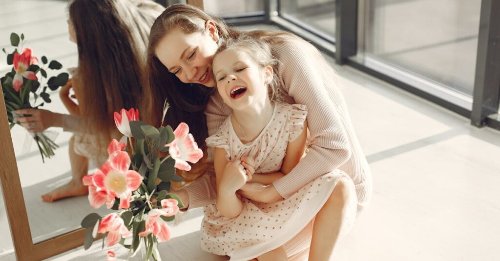 A loving mother and daughter duo laughing joyfully with a bouquet indoors.