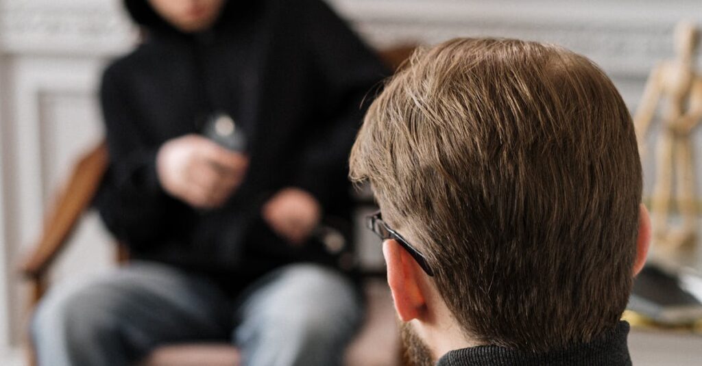 A counselor and patient engaging in a thoughtful therapy session indoors.